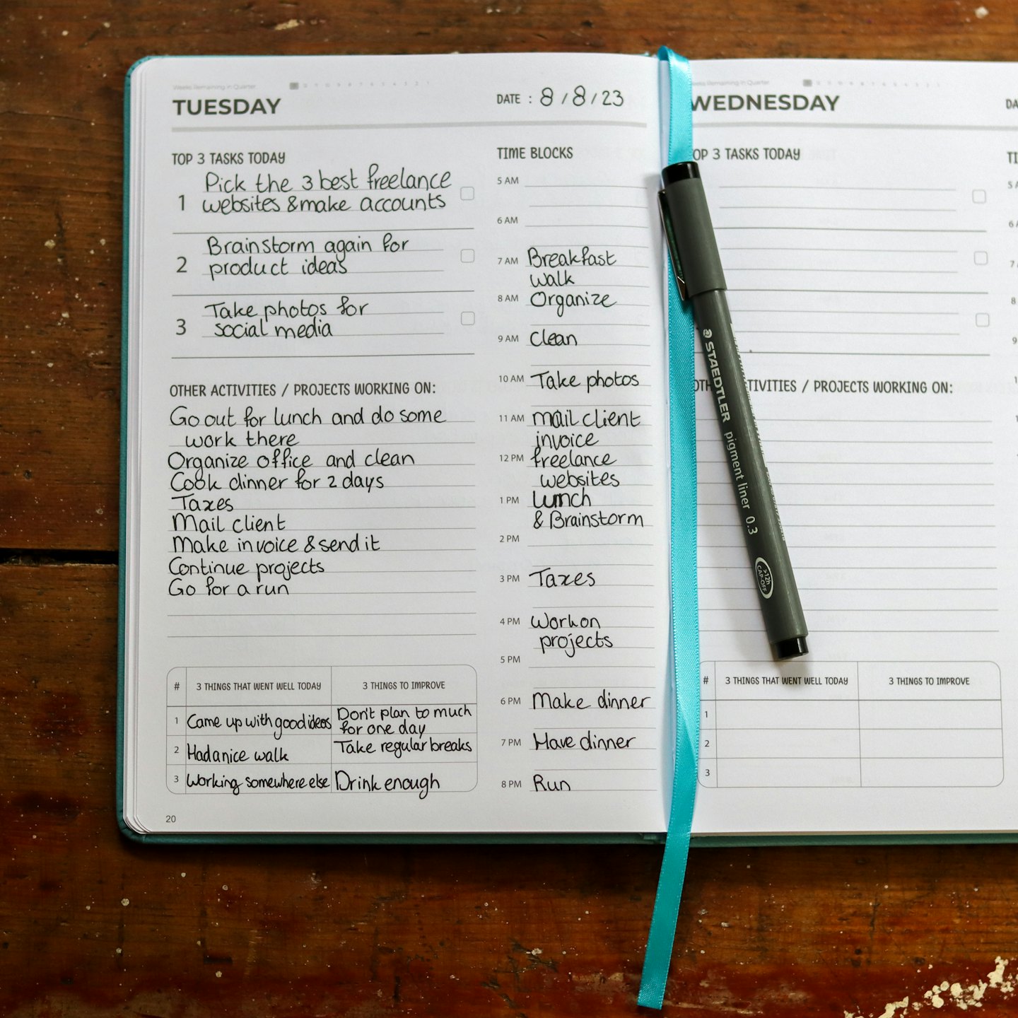 Daily planner open to Tuesday and Wednesday with a pen on the bookmark.